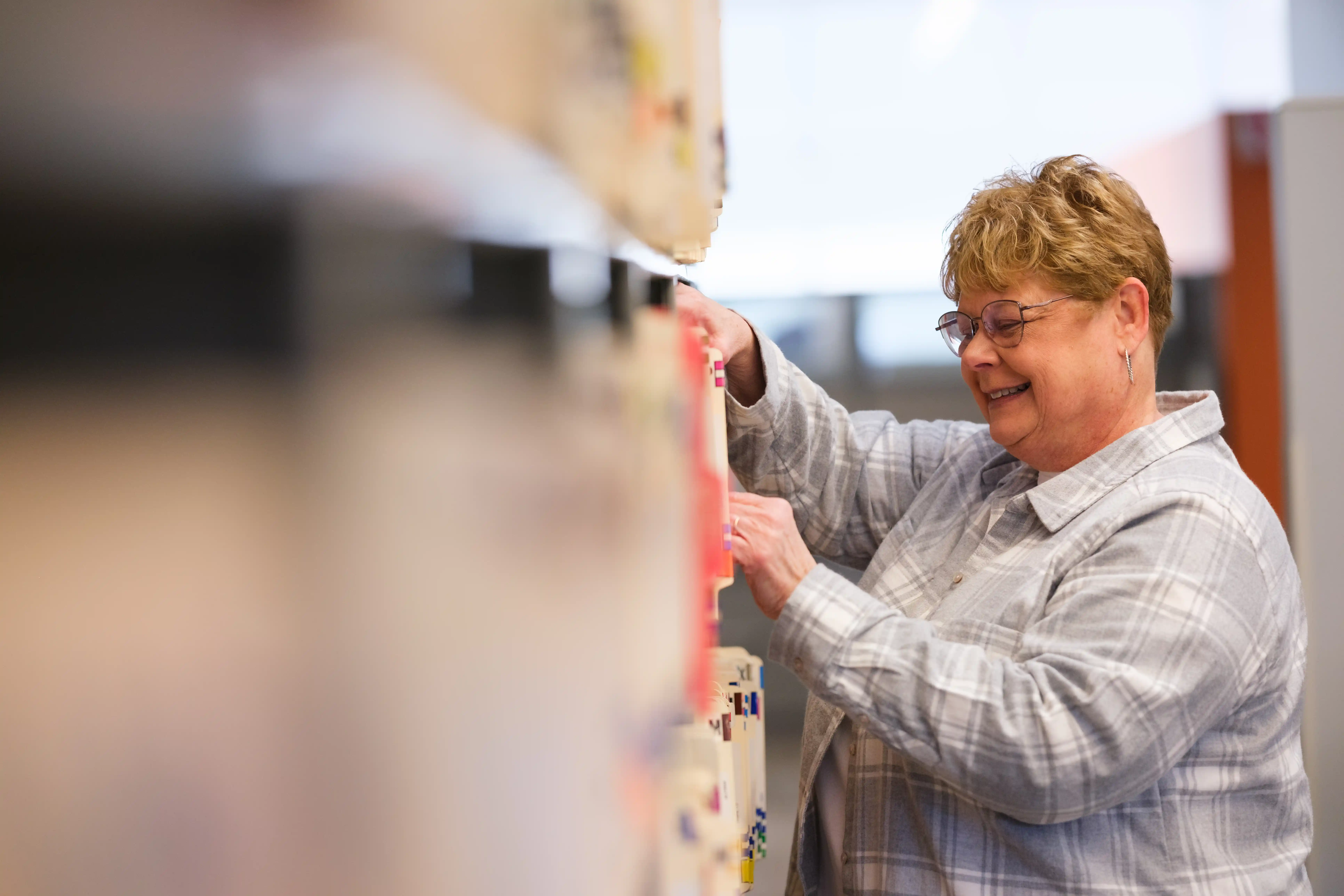Smiling woman sorting through files in a filing system.