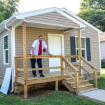 Brian Holland stands on the porch of his new home.