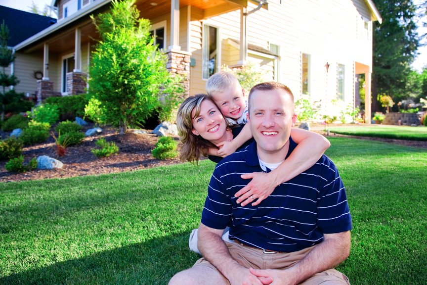 Family of three in front of new home