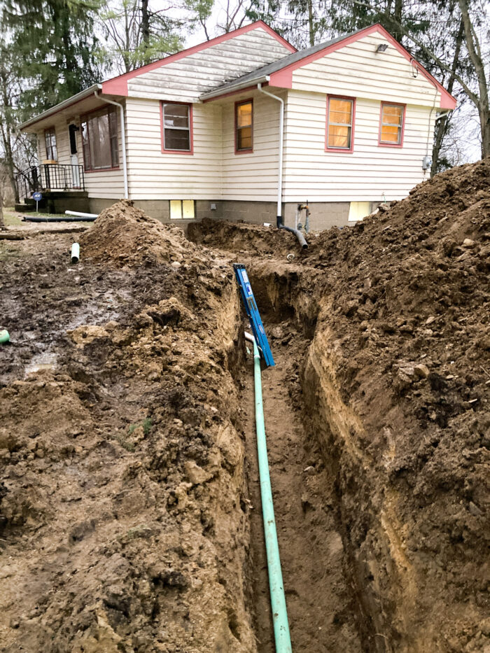 Pipes run through a trench connecting a home to a damaged septic system.