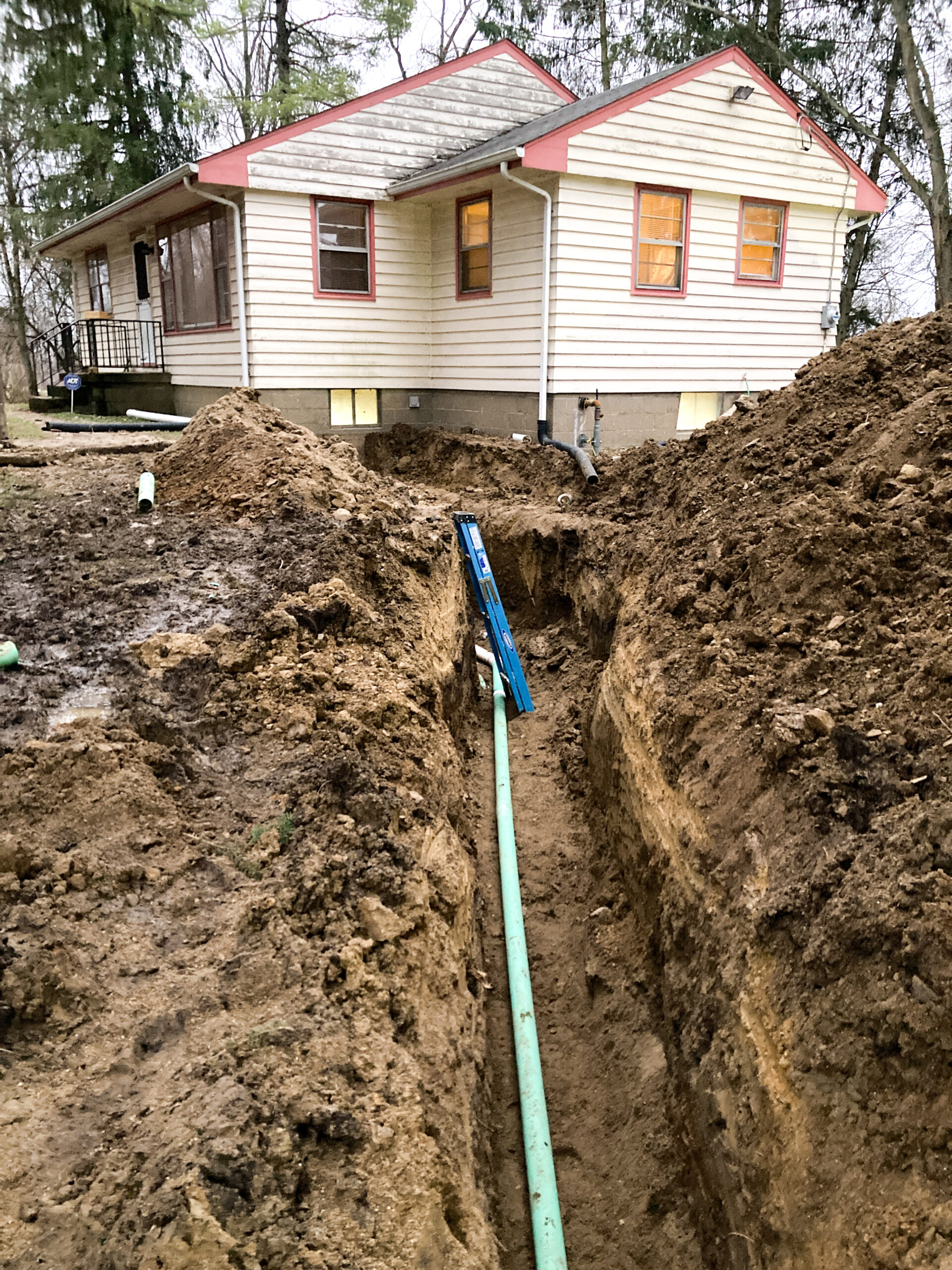 Pipes run through a trench connecting a home to a damaged septic system.
