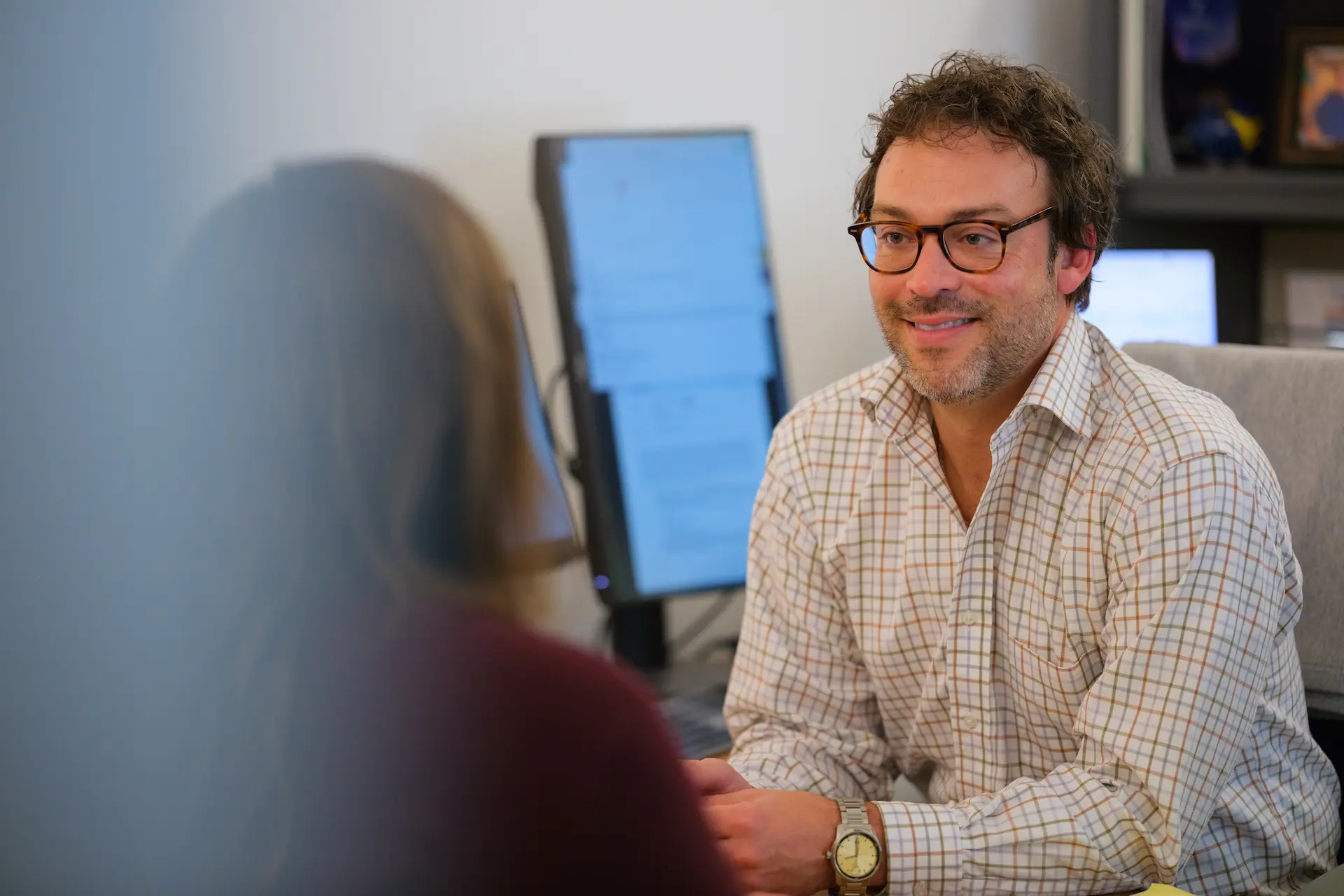 Person engages in conversation across a desk, reflecting a welcoming and supportive office environment.