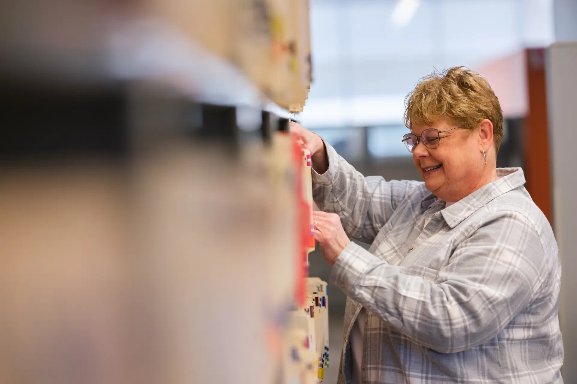 Person organizes files in an office, reflecting attentive support and day-to-day service work.