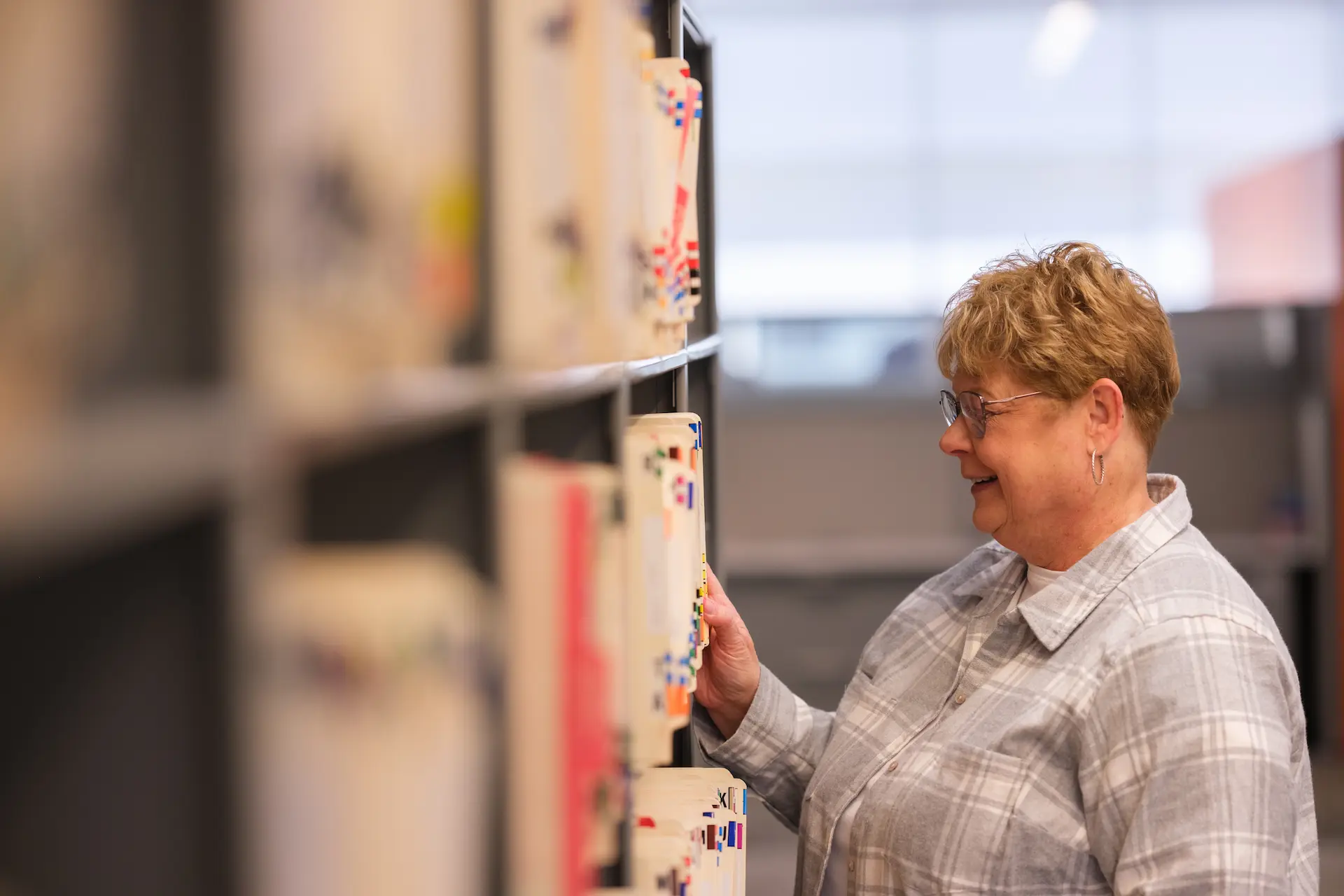Person retrieves a file from organized office records shelves.