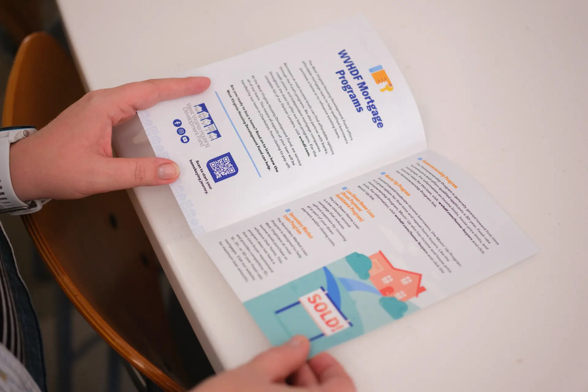 Person reviews a West Virginia Housing Development Fund mortgage programs brochure.