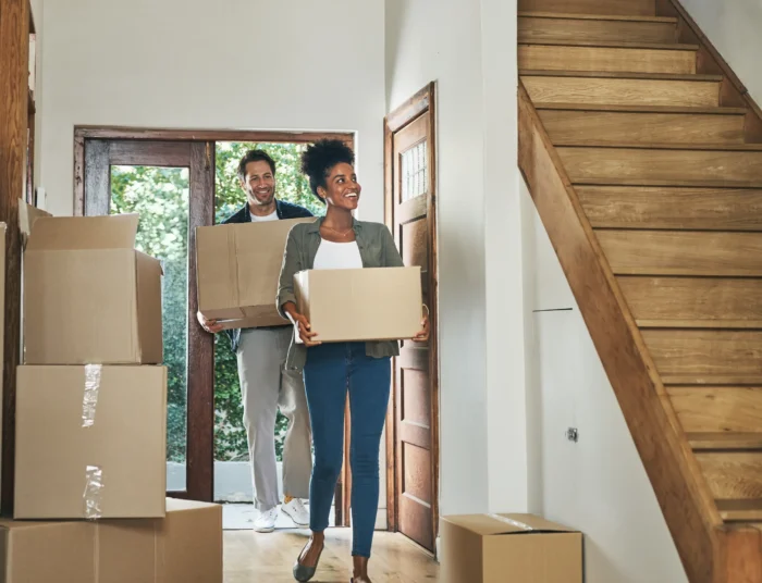 Couple carrying moving boxes into their new home.
